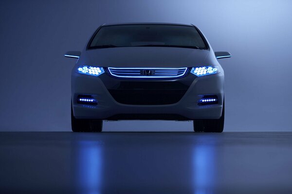 Honda with headlights on on a blue background