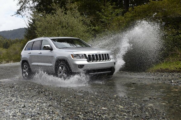 Jeep conduce fuera de la carretera, salpicaduras en diferentes direcciones