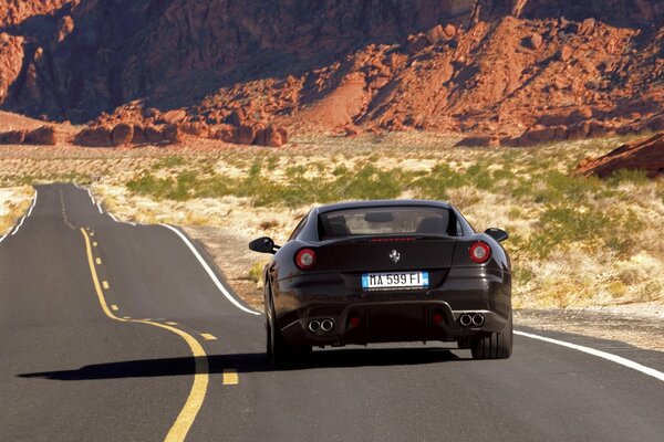 Ferrari auf der Straße in der Wüste vor der Rückseite