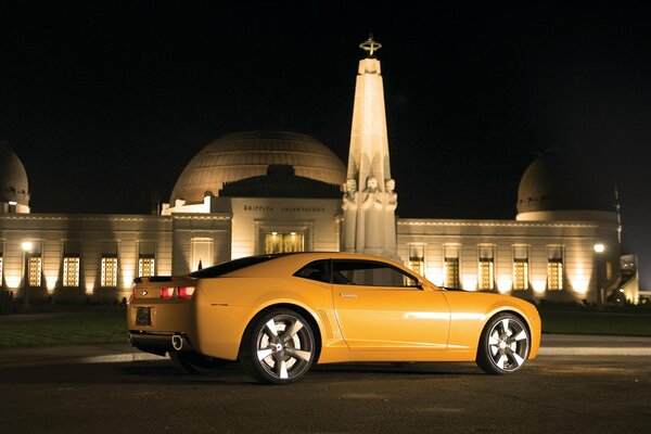 Voiture Chevrolet jaune dans la nuit près du bâtiment