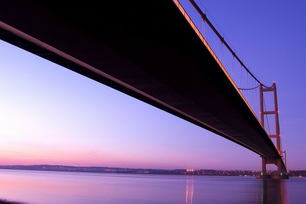 Der violette Sonnenuntergang ist über die Brücke sichtbar