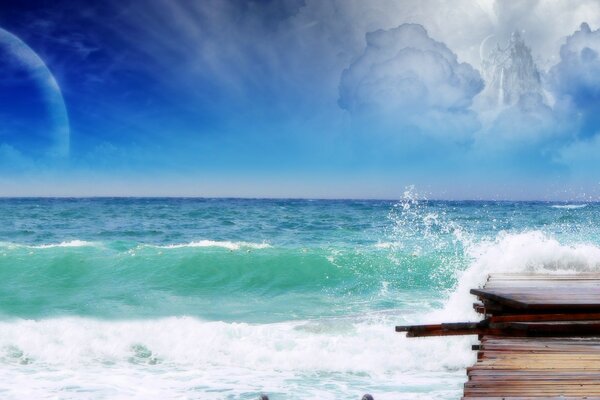 Green sea waves break on the pier under the blue sky, in which an air castle of clouds can be seen