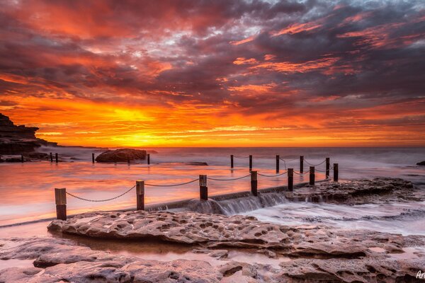 Stones on the sea pier and a sunset in the clouds in the sky