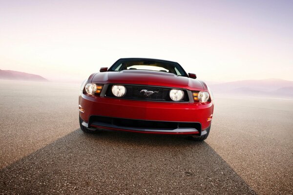 Ford Mustang rojo en la carretera bajo el sol