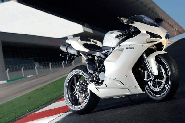 Vélo de moto blanc se dresse sur le fond du bâtiment