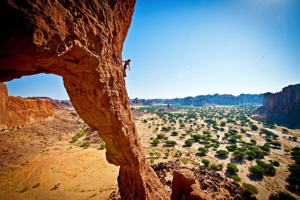 Ein Mann klettert in einer verlassenen Schlucht über einen Felsen