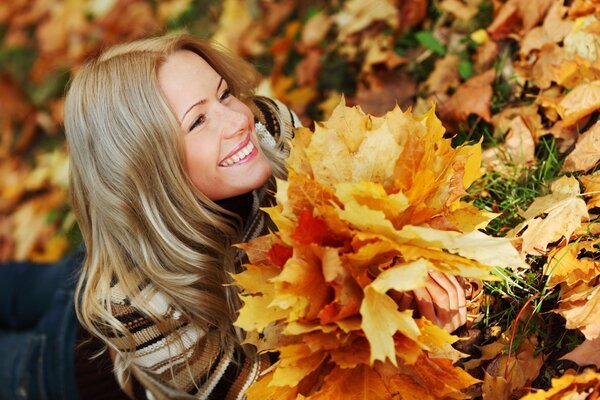 Smiling girl with a bouquet of fallen leaves