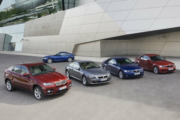 Nel parcheggio ci sono cinque BMW colorate. In primo piano quattro, e un altro sul retro