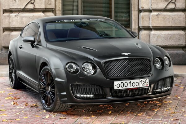 Bentley noir sur des pavés avec des feuilles mortes