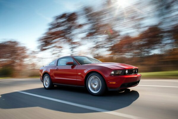 Ford Mustang rojo corriendo por la carretera