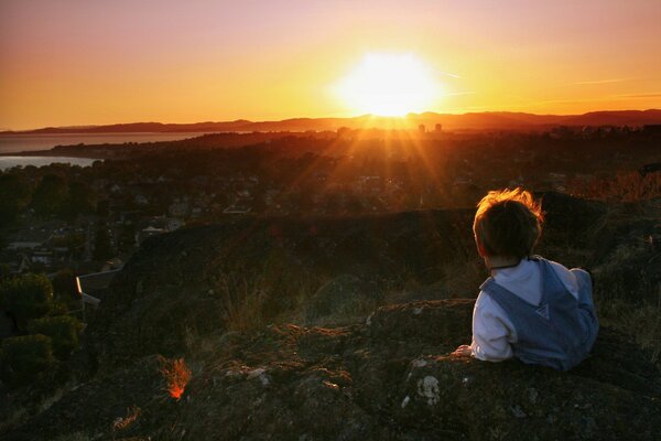 A child in the morning against the background of the red sun setting