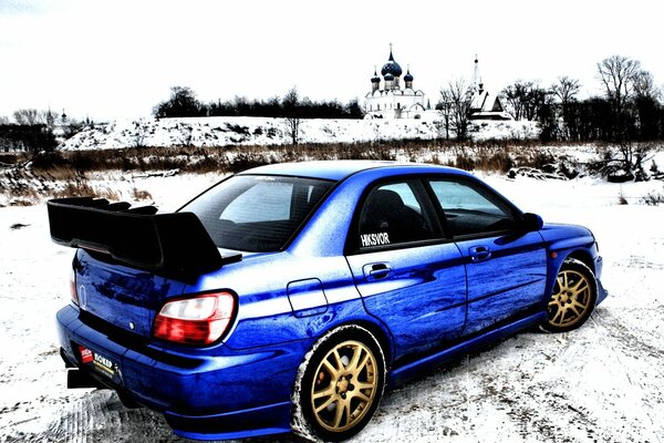 A blue Subaru stands against the background of the cathedral