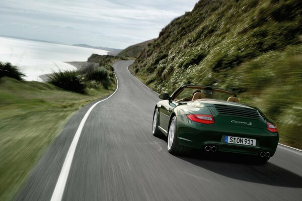 La Porsche verde scuro si muove lungo la strada ad alta velocità