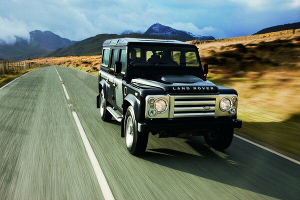 A black rover is driving on an asphalt road