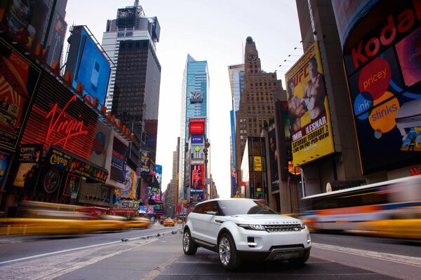 Rover on the road in a megalopolis among advertisements and skyscrapers