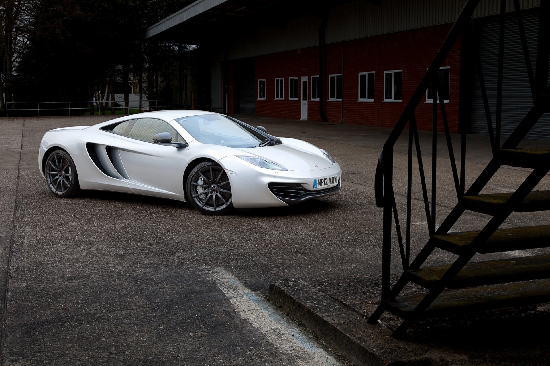 mclaren mp4-12c серебристо макларен серебристый вид сбоку чёрные диски лестница здание окна дверь