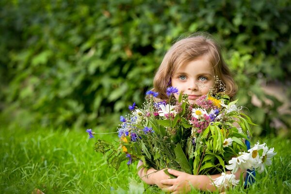 Niña con un gran ramo de flores de pradera