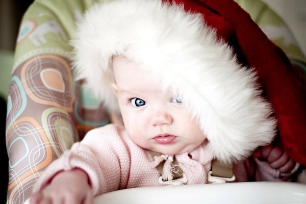 Niño con sombrero de año nuevo. Niño de ojos azules en la silla alta
