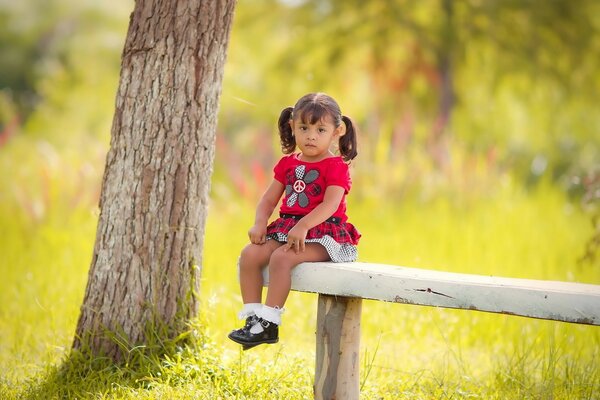 A girl sits on a bench in summer