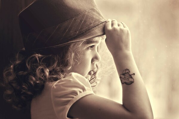 A little girl in a hat looks into the distance