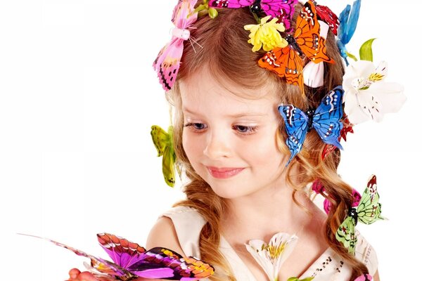 Una niña con una flor sostiene una mariposa en su mano