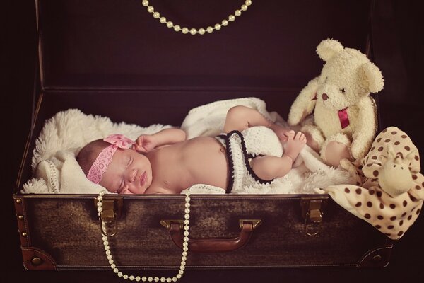 Baby sleeps in an antique suitcase