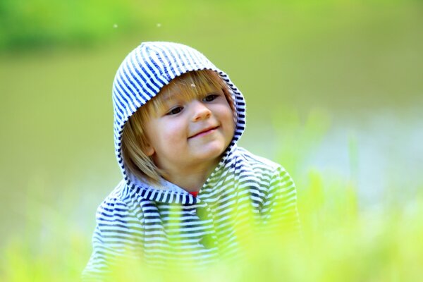 A child in a striped hood on a green background