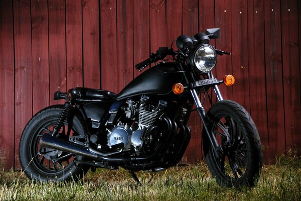 Мотоцикл xj 650 на траве на фоне деревянного забора