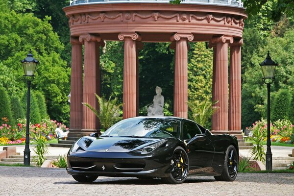 A black Ferrari stands near the column in Italy