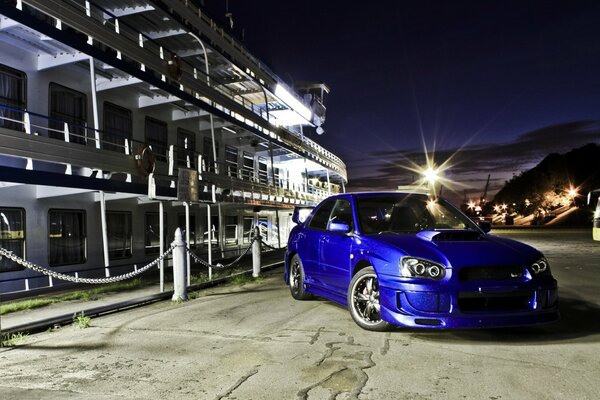 Blue subaru impreza on the pier next to the ship