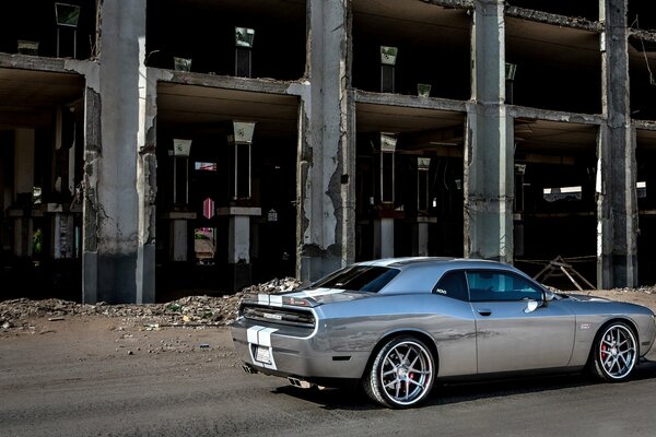 Grey challenger car on the background of the building side view