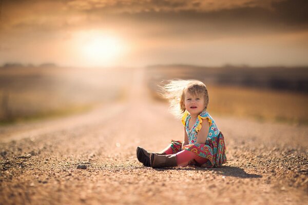 A child on the road against the background of sunset positive