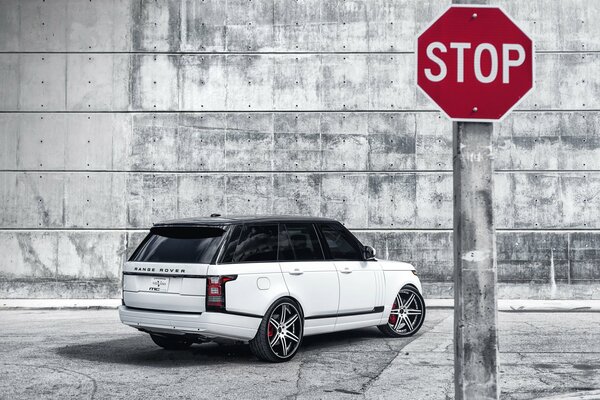 Segnale di stop su Won Range Rover bianco e muro di pietra