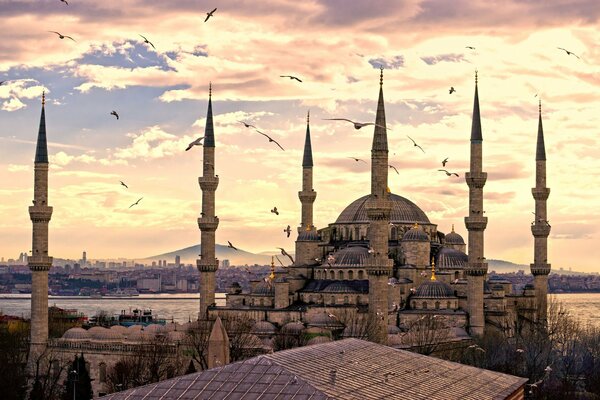 Türkische Moschee vor dem Hintergrund von Vögeln und goldenen Wolken