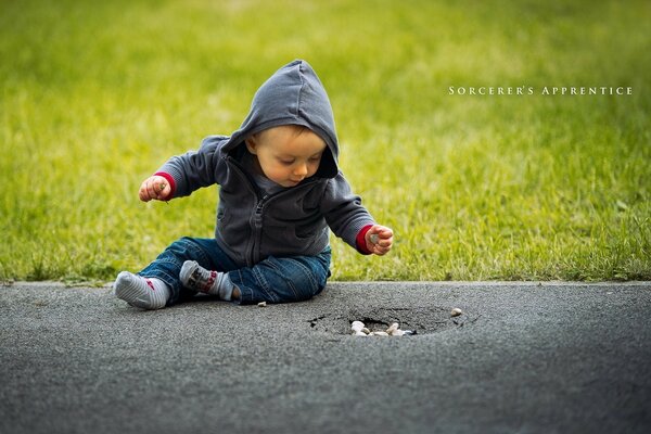 A little boy is sitting on the asphalt