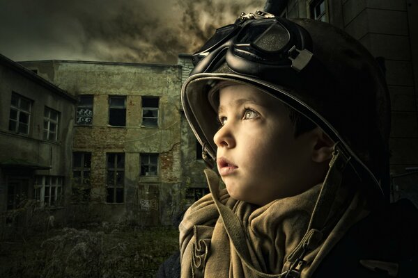 Маленький мальчик смотрит в небо на фоне заброшенного здания