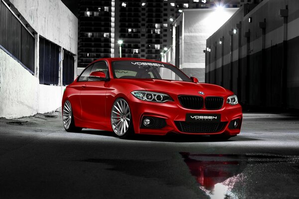 Red BMW 220d on the background of a black and white city