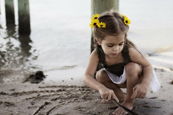 A girl with a wreath on the sandy shore plays