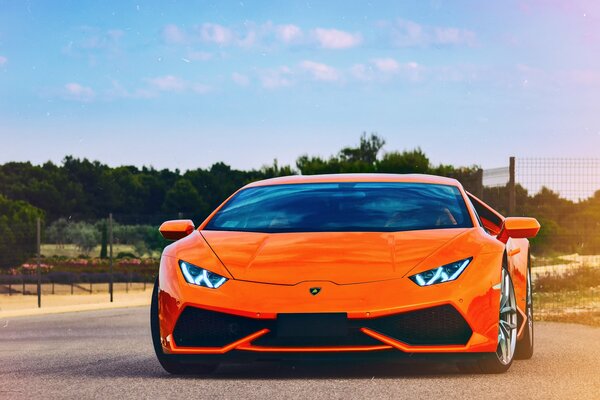 Orange Lamborghini URACAN chevauche la route sur fond de forêt