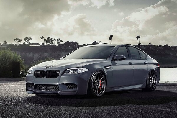 Tuning bmw M5 debout sur le rivage sur fond de ciel nuageux