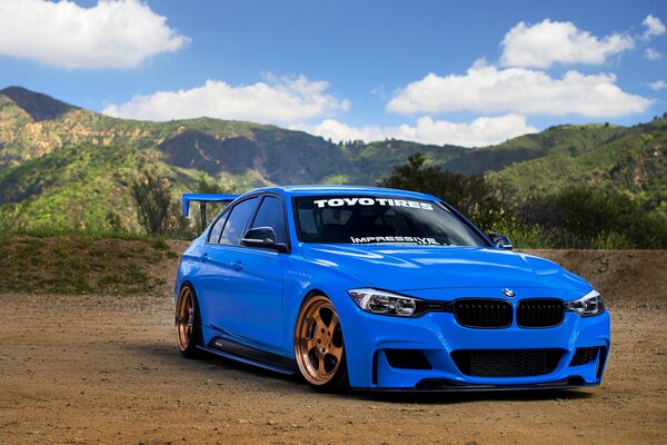 BMW 3 series car in blue on the background of mountains
