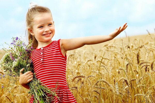 A child with a bouquet of flowers in a wheat field