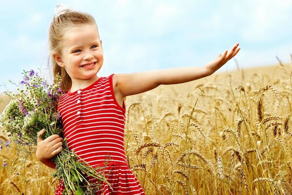 Niño con un ramo de flores en un campo de trigo