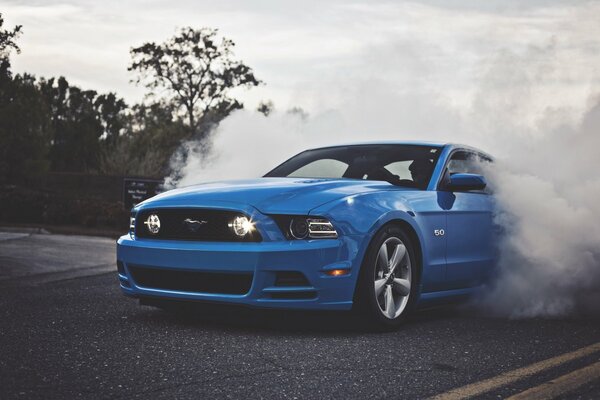 Blu Ford Mustang sulla strada nel fumo