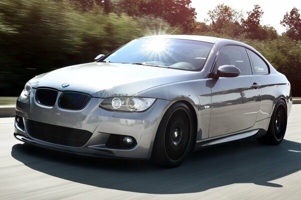 BMW Monte sur la route en jouant l éblouissement du soleil