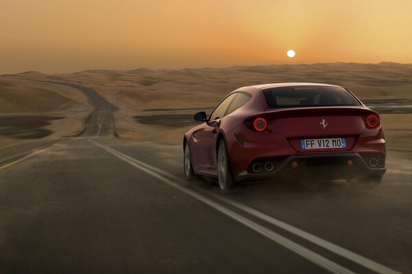 Coche rojo conduce por la carretera en el desierto