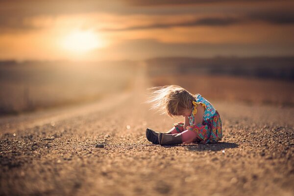 A lonely child is sitting on the road