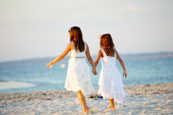 Two girls on the beach holding each other s hands