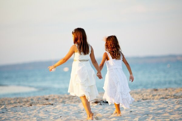 Dos chicas en la playa se toman las manos