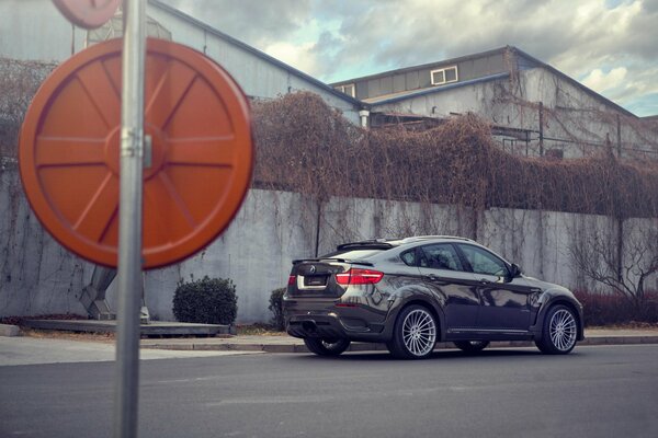 A gray bmw on wheels Hamann stands near the wall